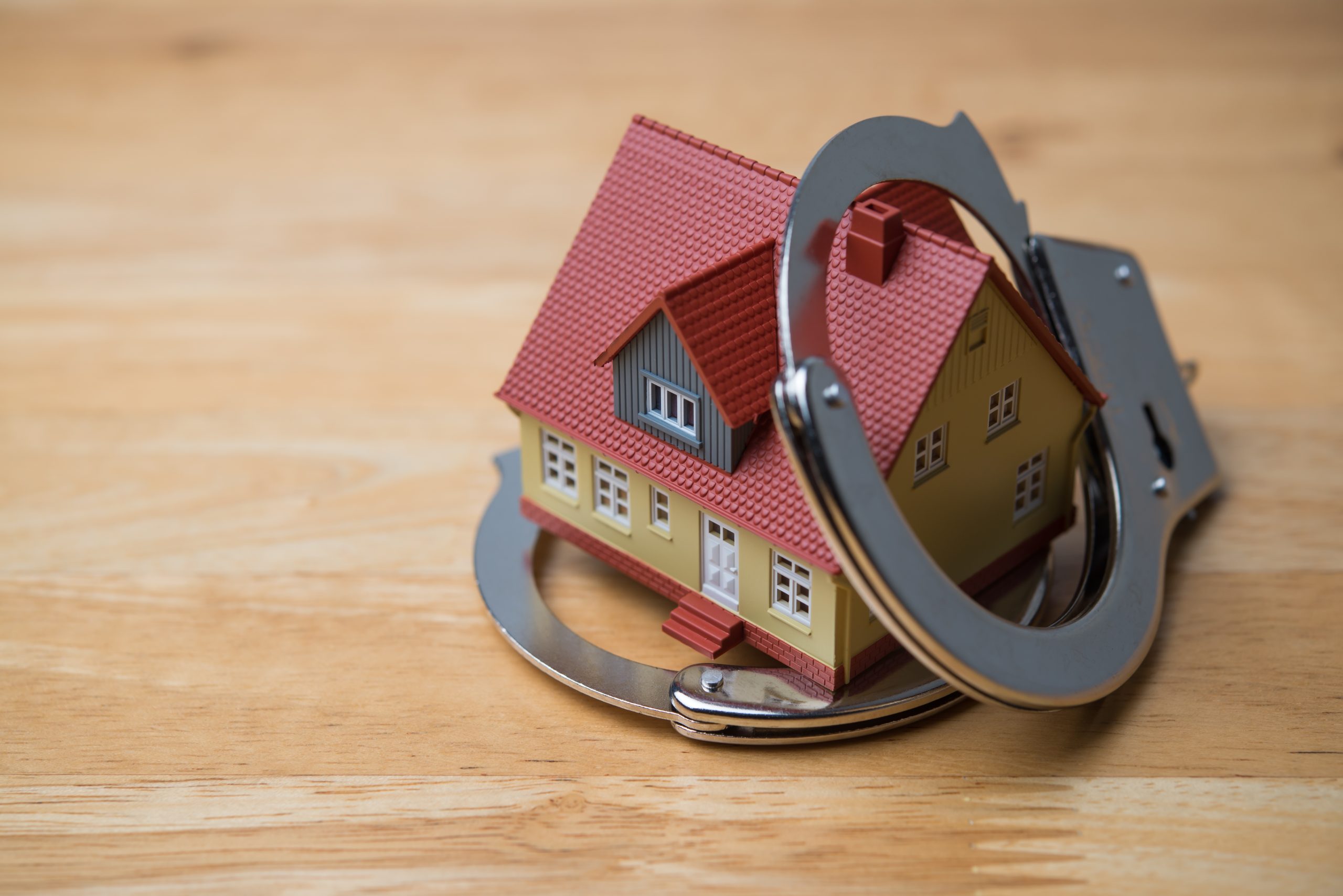 House,And,Handcuffs,Police,On,Wooden,Table,Background.,Real,Estate,